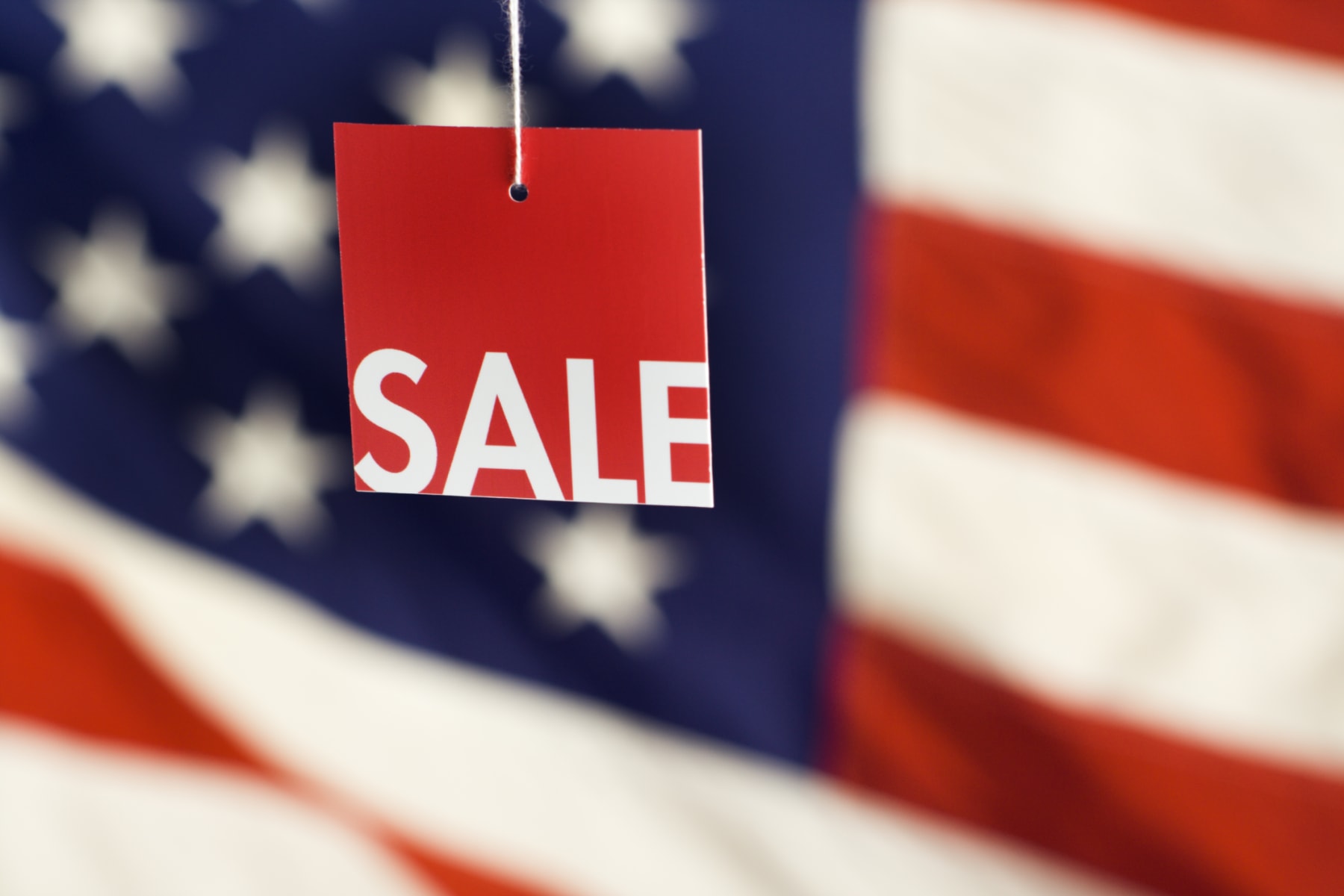 Sale sign hangs in front of American flag.
