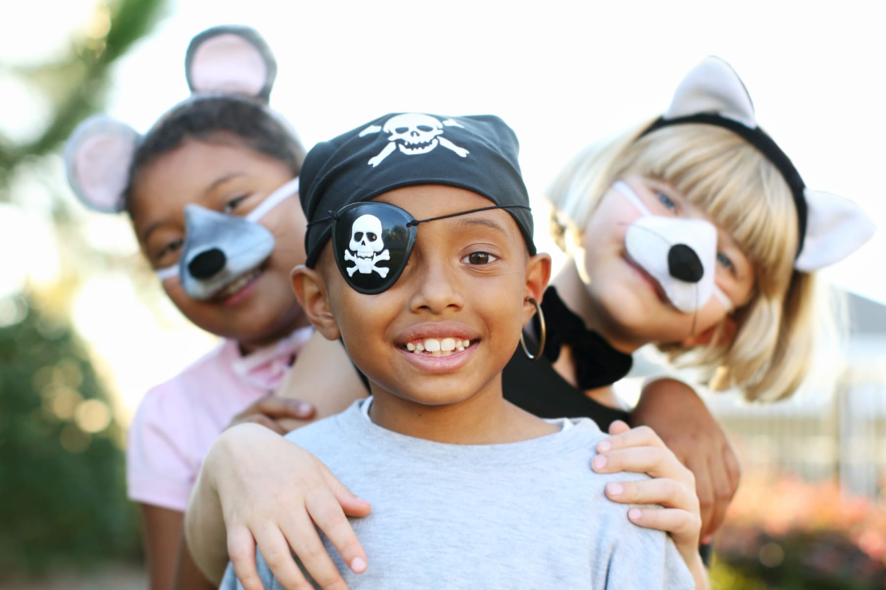 Three kids wearing Halloween costumes pose for camera.