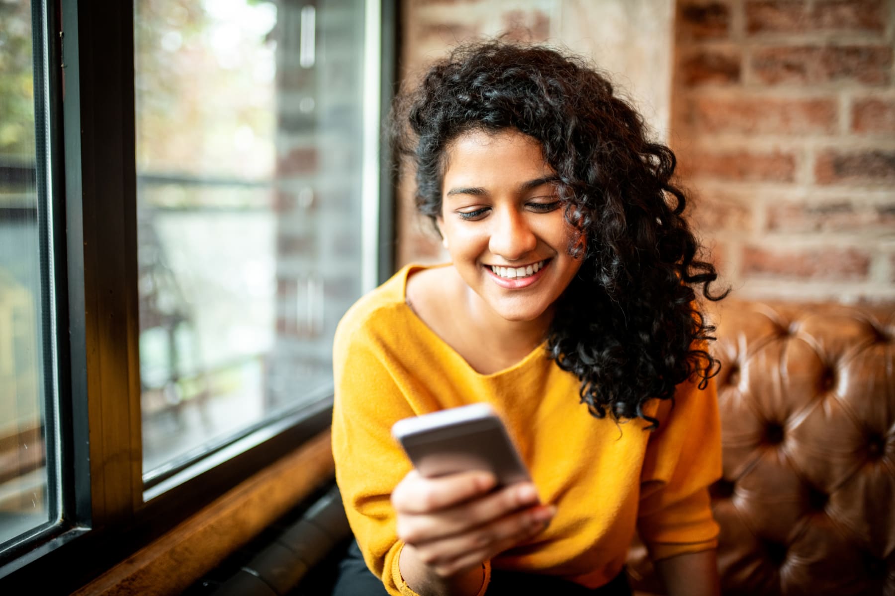 Smiling woman uses mobile phone.