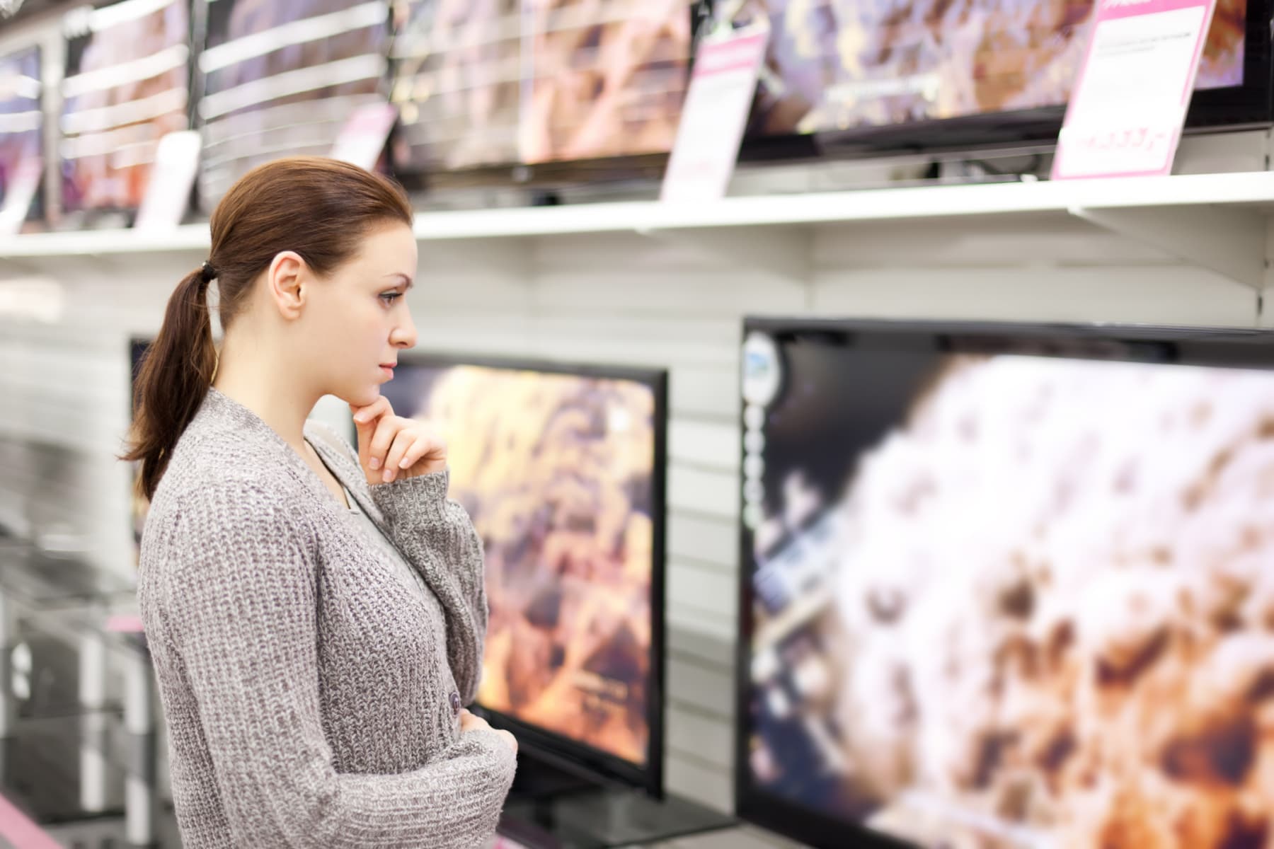 Woman checks out televisions while browsing in store.