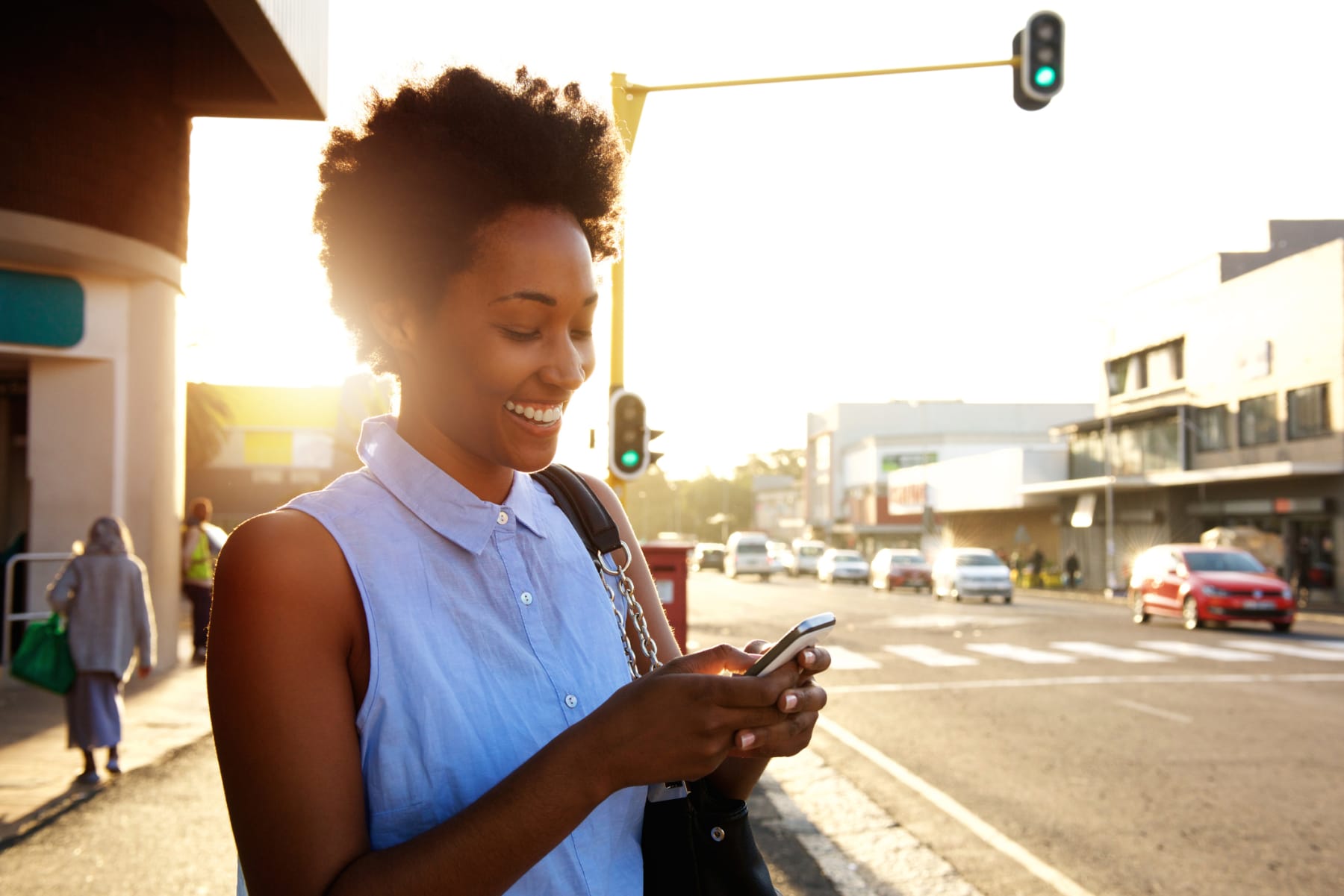 Black woman uses phone on street.