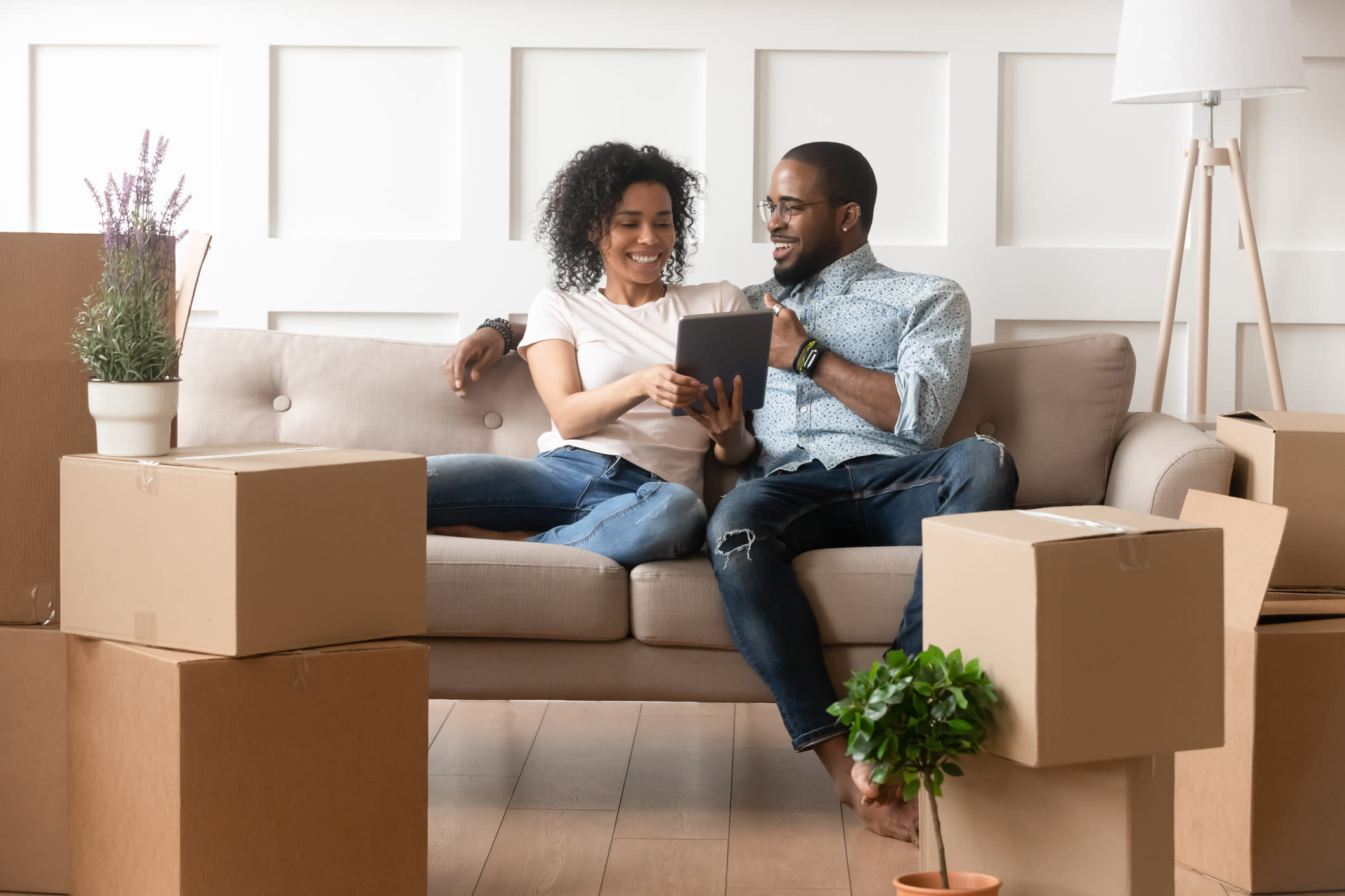 Couple Sits on a Couch Looking at a Tablet